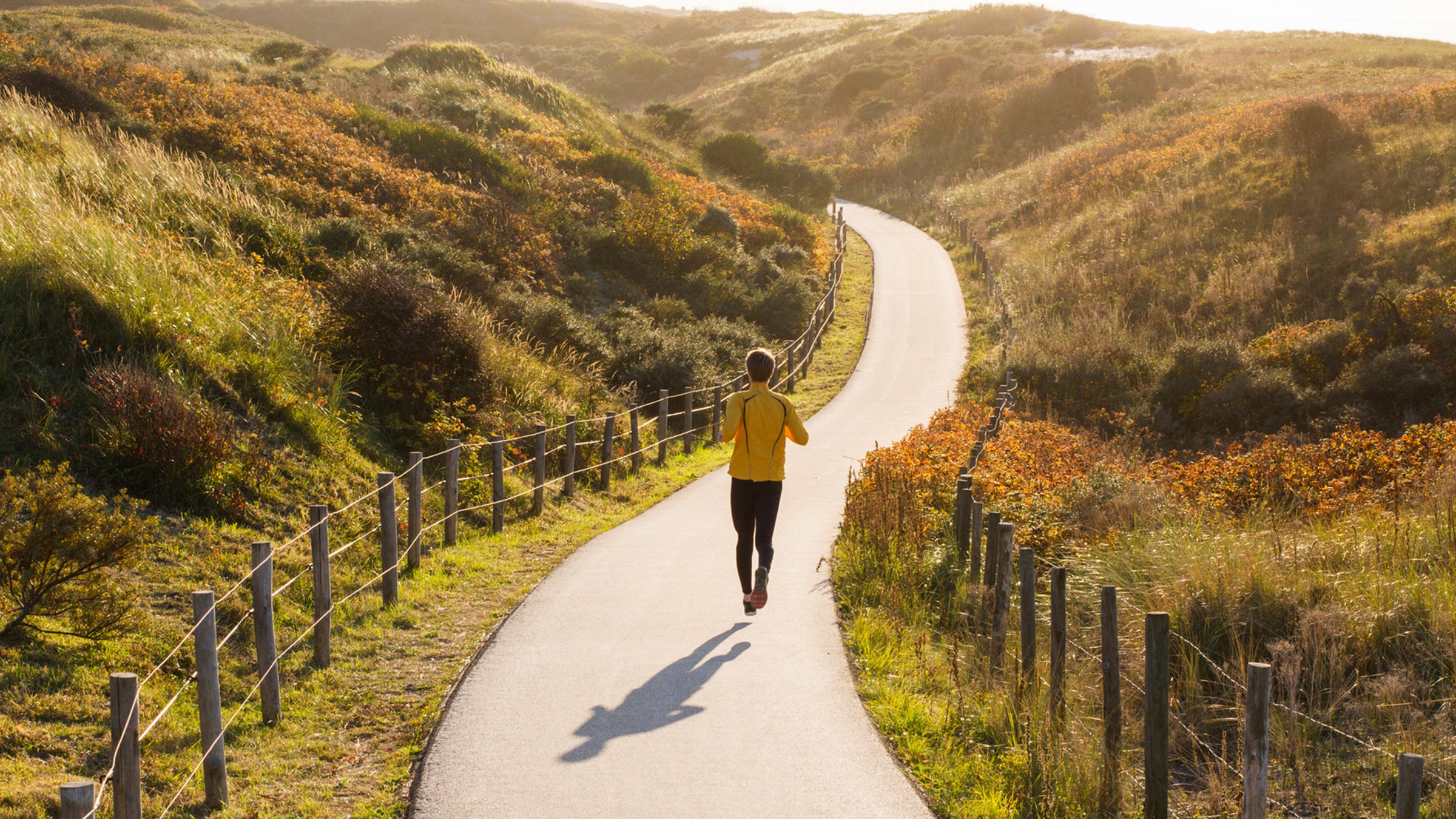 Young Caucasian Man Running In The Dunes During Sunset.
