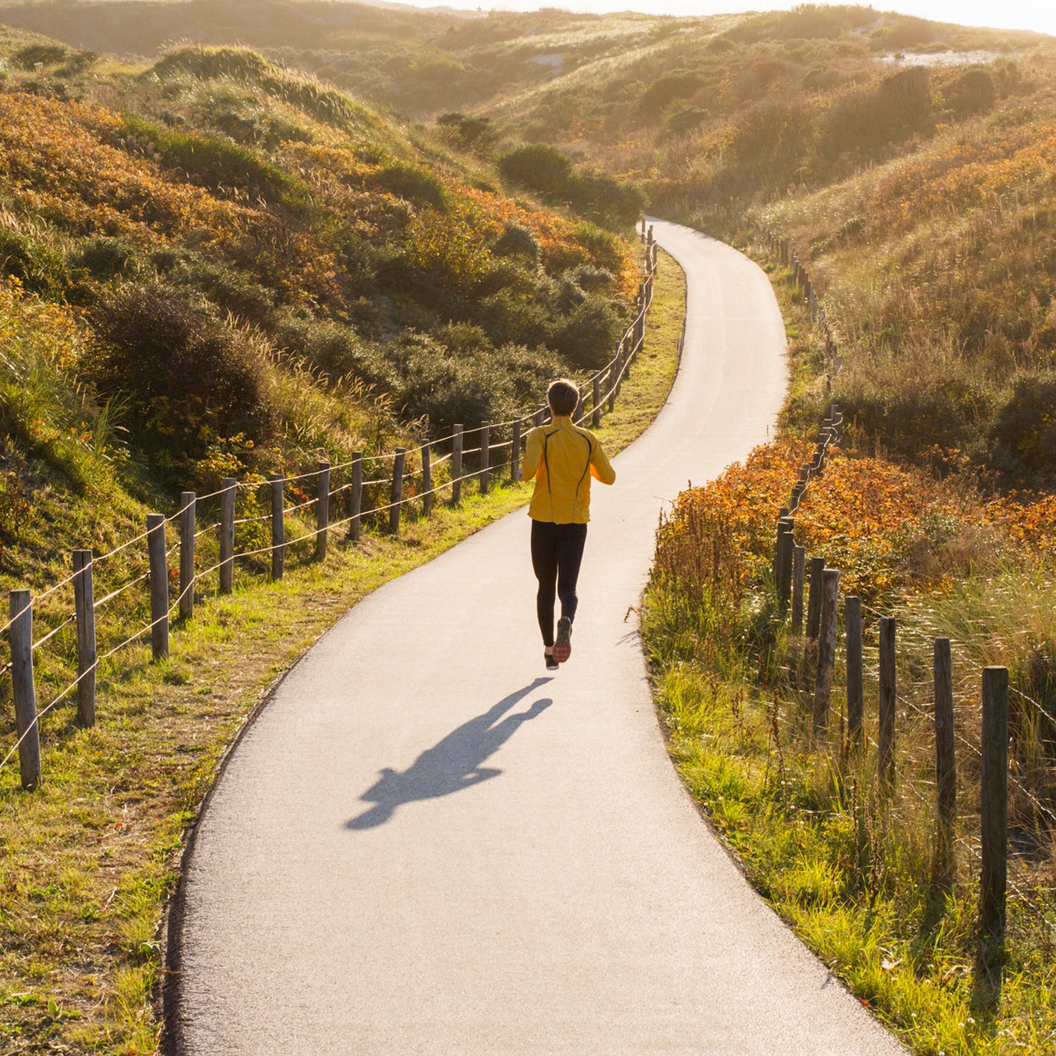 Young Caucasian Man Running In The Dunes During Sunset.