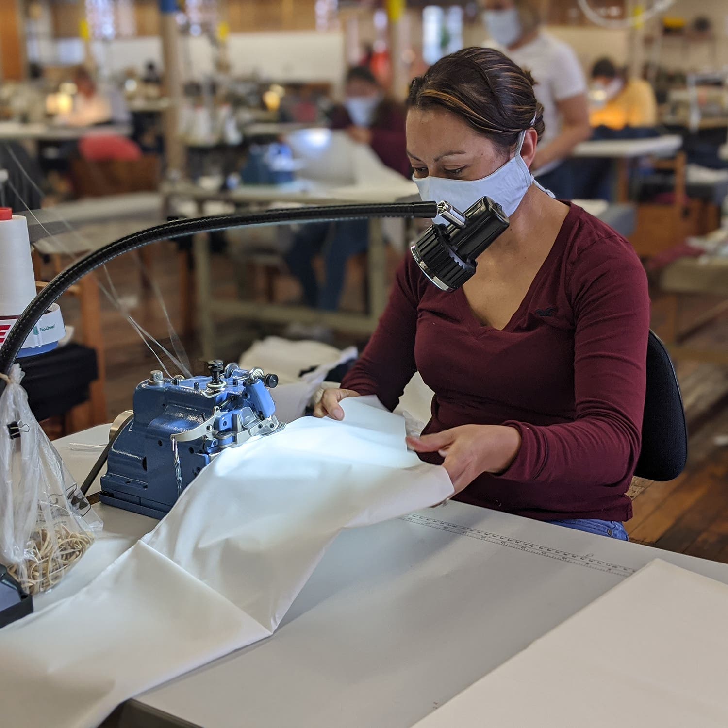 woman wearing face mask using a sewing machine to make a gown