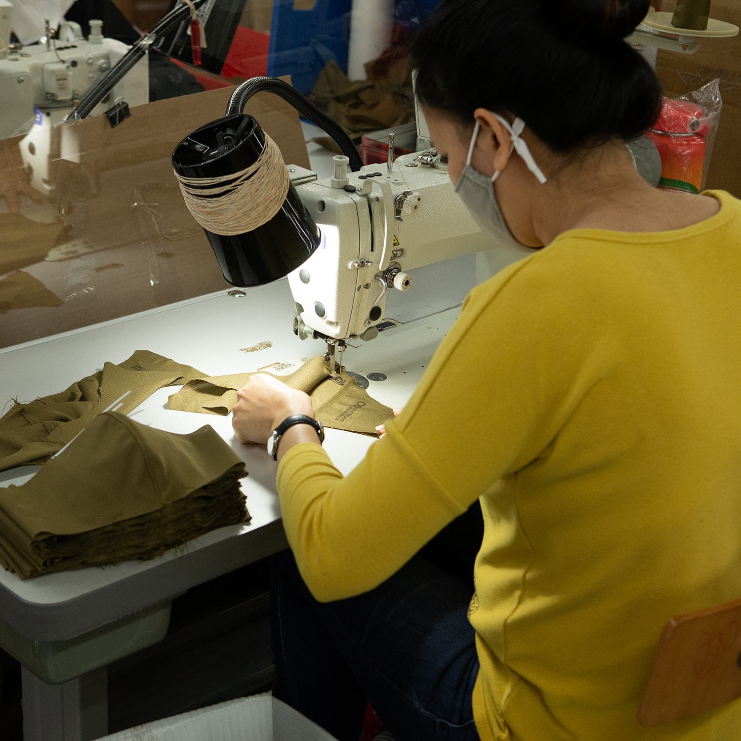 woman in yellow sweater using a sewing machine