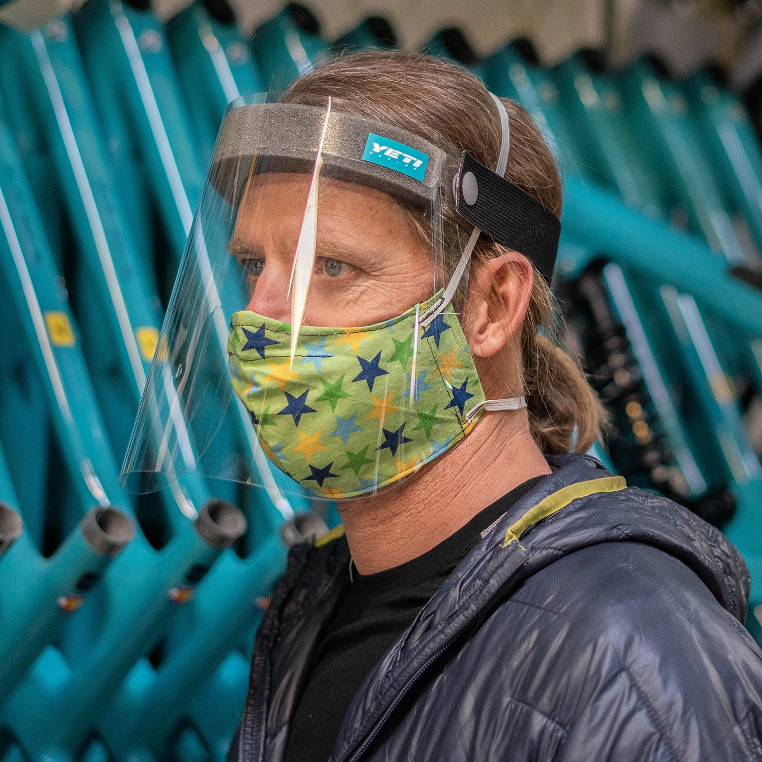 man wearing a face mask and face shield in front of bike frames