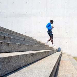 young sportsman running down steps in front of concrete wall outdoors in berlin at sunny day