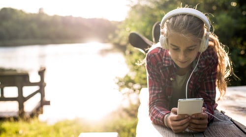 Young girl using smartphone at the lake