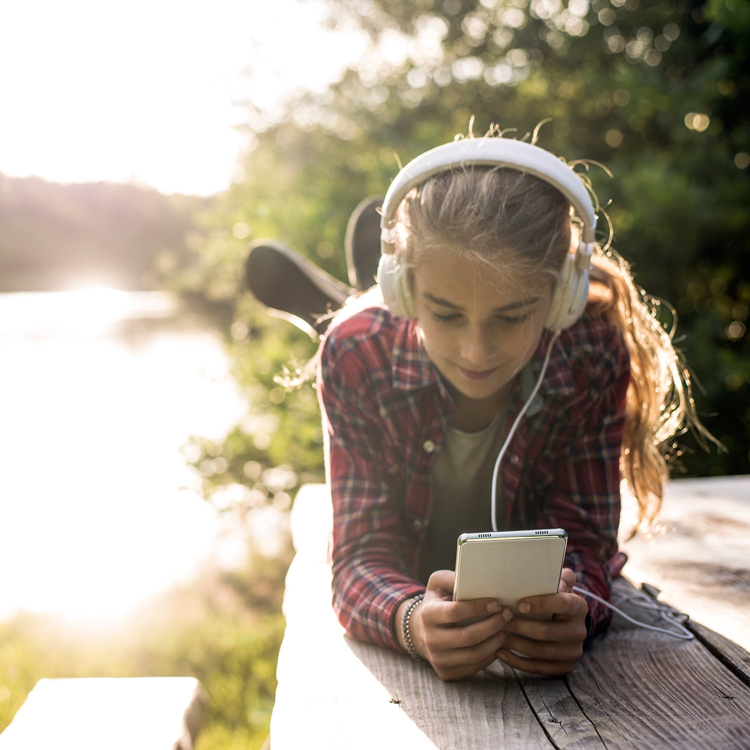 Young girl using smartphone at the lake