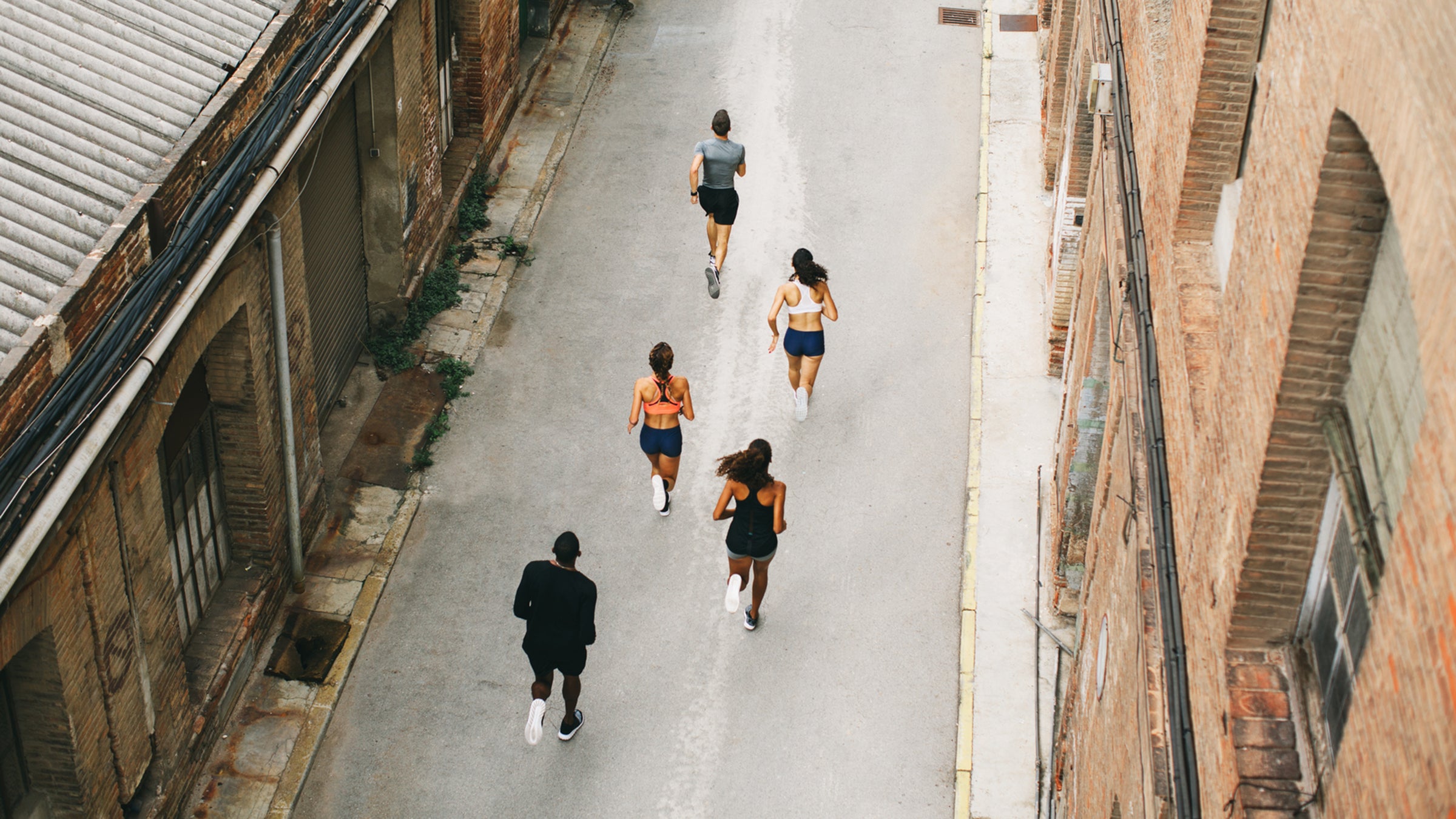 Group Of Athletes Running On The Street From Above.
