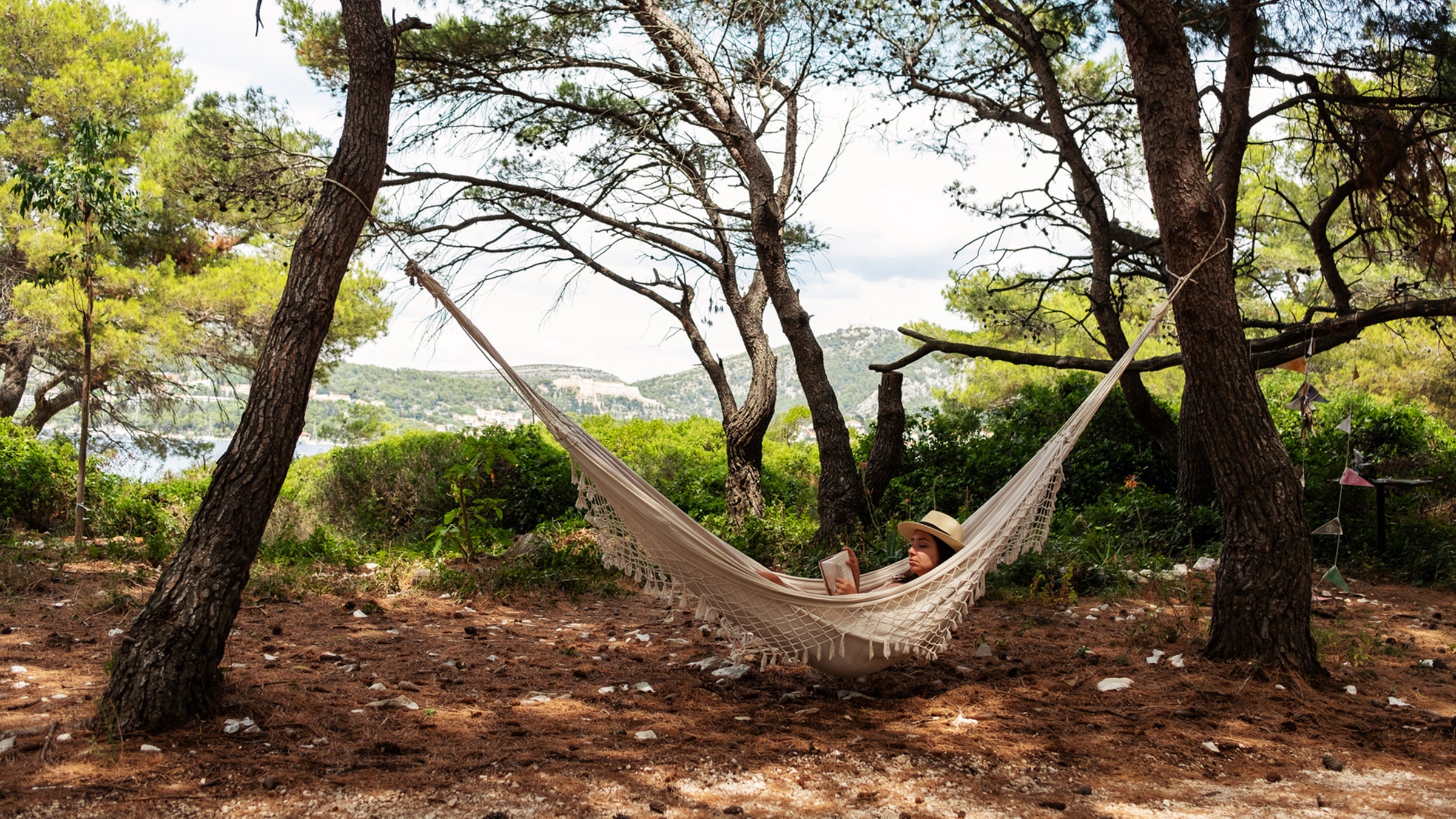 Woman Lying In Hammock And Reading A Book