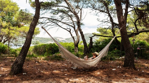 Woman Lying In Hammock And Reading A Book