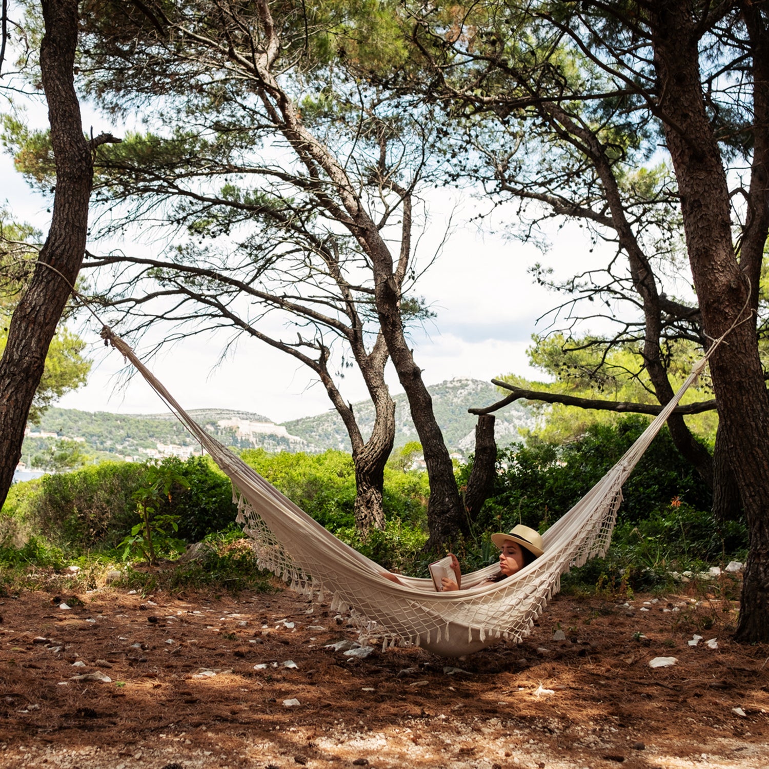 Woman Lying In Hammock And Reading A Book