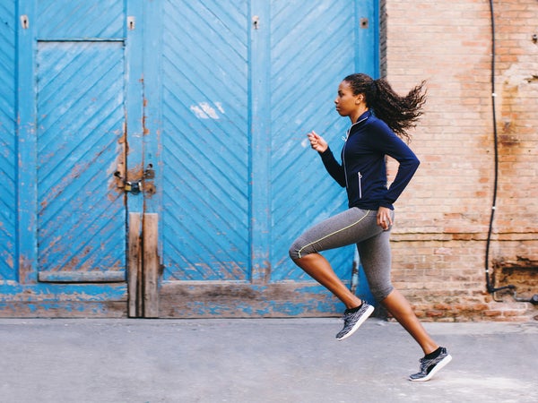 Side View Of An African American Woman Running On The Street.