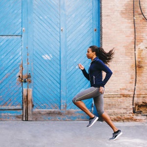 Side View Of An African American Woman Running On The Street.
