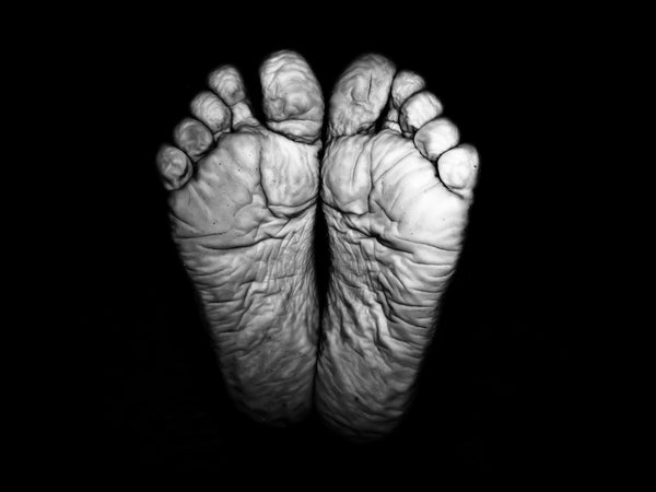 A black and white photo of the bottom of wrinkled feet