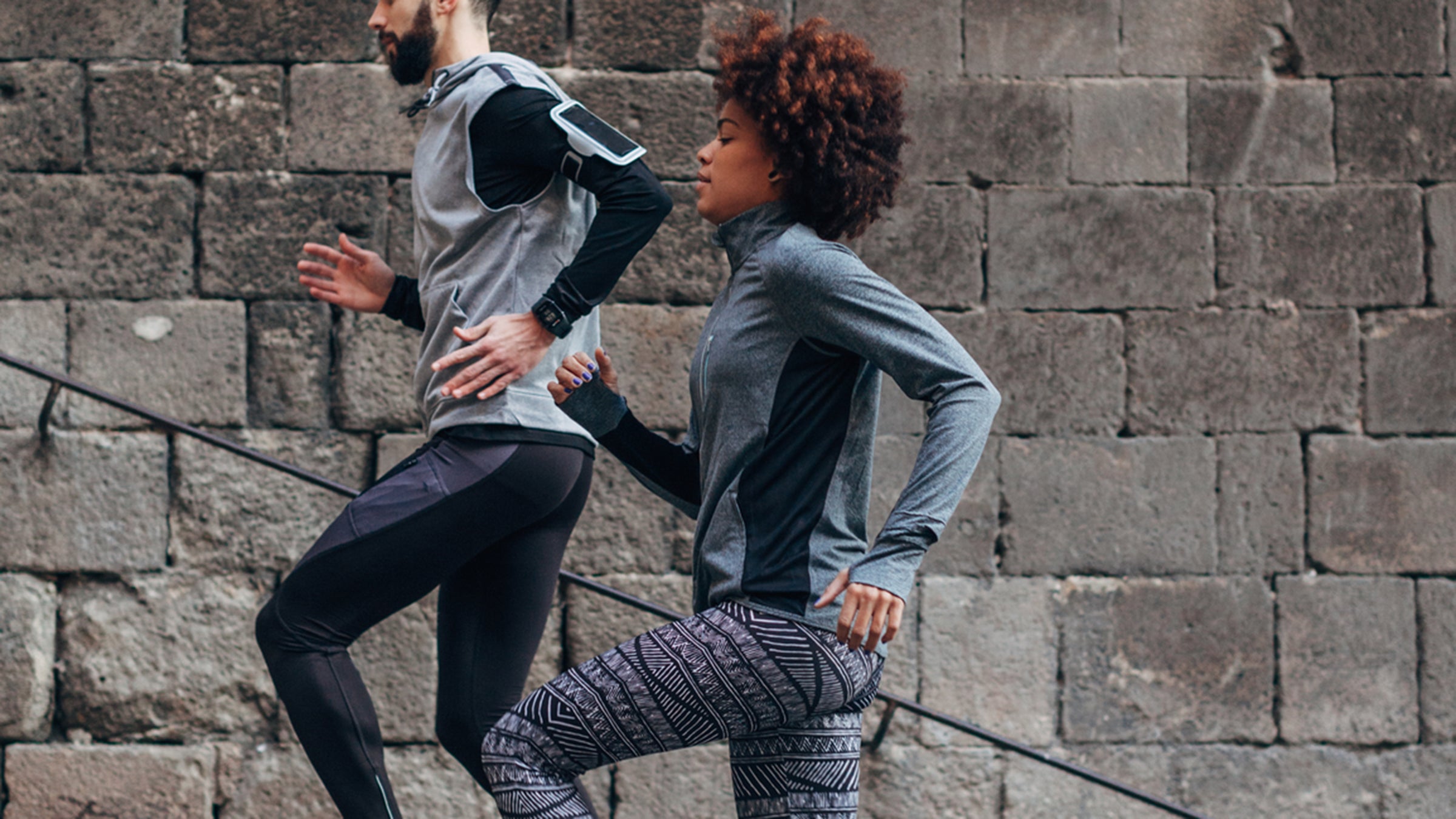 Young Multiethnic Couple Running Of Old Steps Outside.