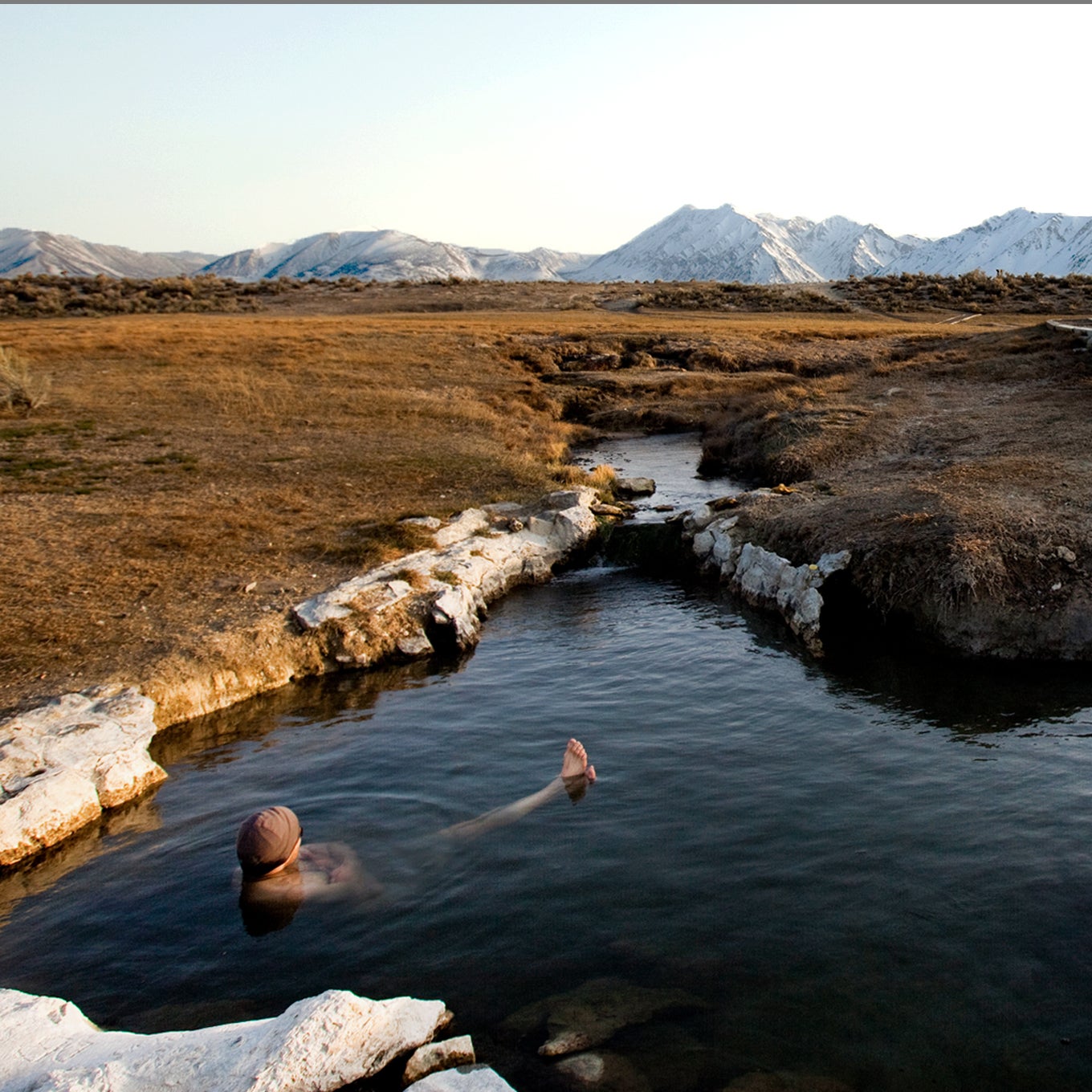 A man enjoys a hot spring near the mountains in California.