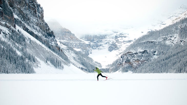 A young woman Nordic skiing across a frozen Lake Louise in Banff National Park.