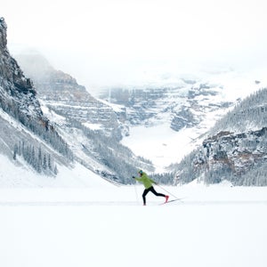 A young woman Nordic skiing across a frozen Lake Louise in Banff National Park.