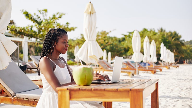 Woman working on laptop on beach