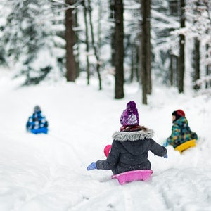 Children sledding in winter forest.