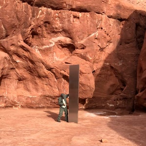 A Utah state worker inspecting a metal monolith
