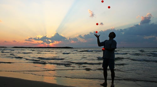 A talented juggler juggling in front of a body of water