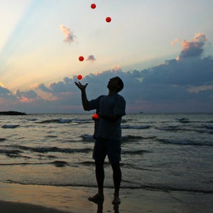 A talented juggler juggling in front of a body of water