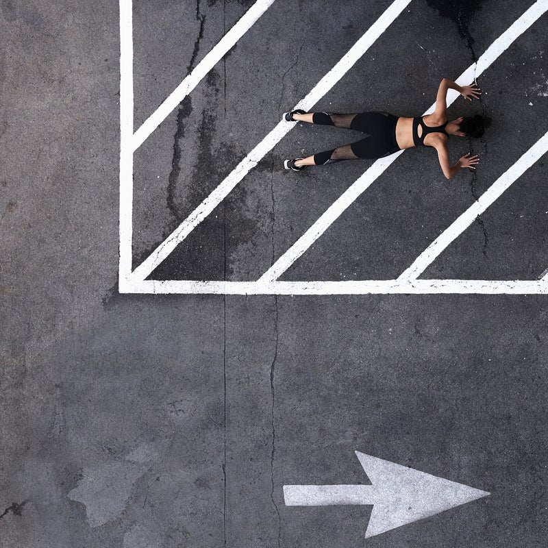 Aerial view of Pacific Islander woman doing push-ups in parking lot