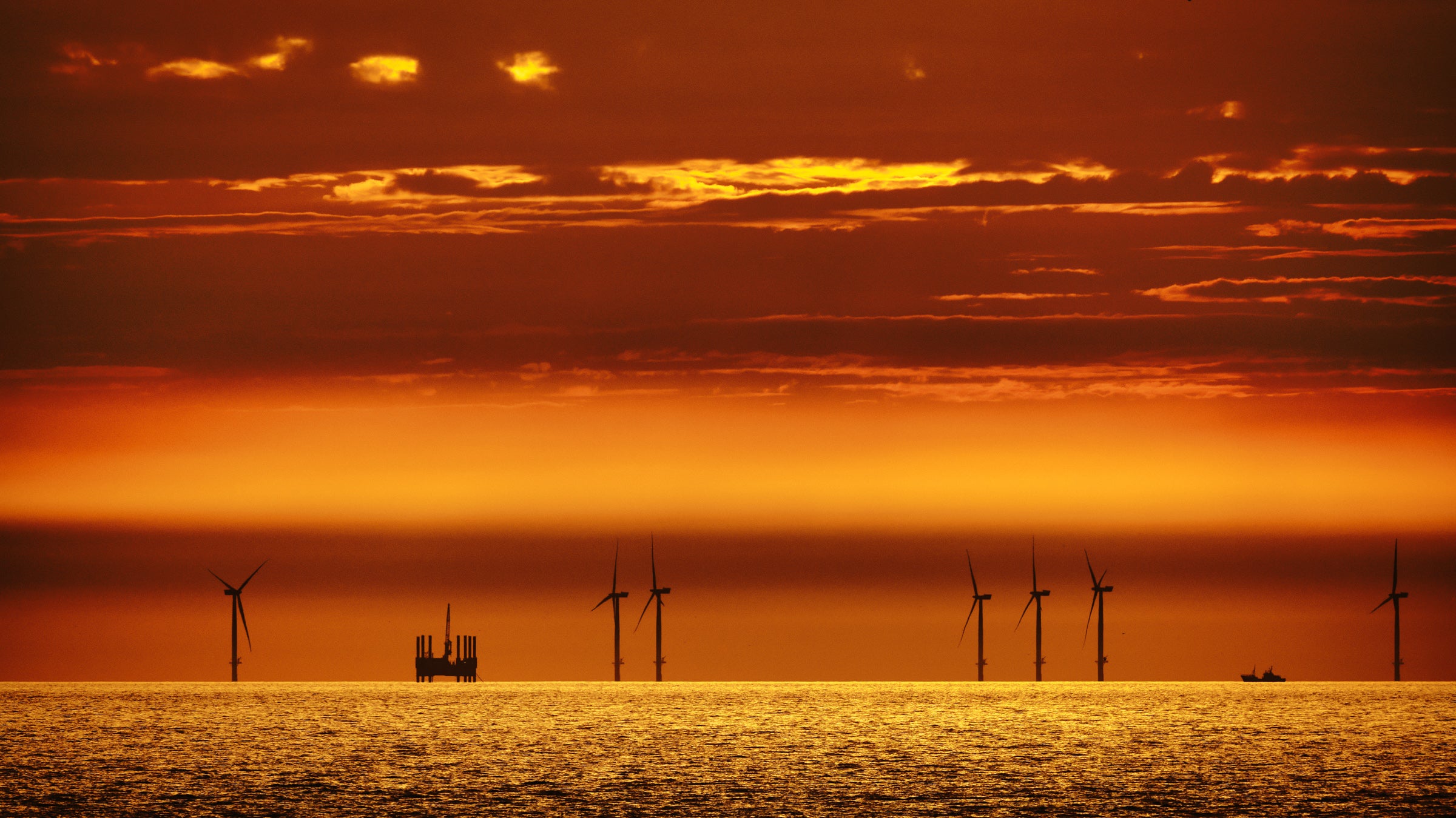Offshore windmills alongside an oil rig