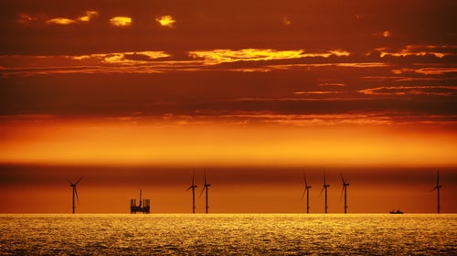 Offshore windmills alongside an oil rig