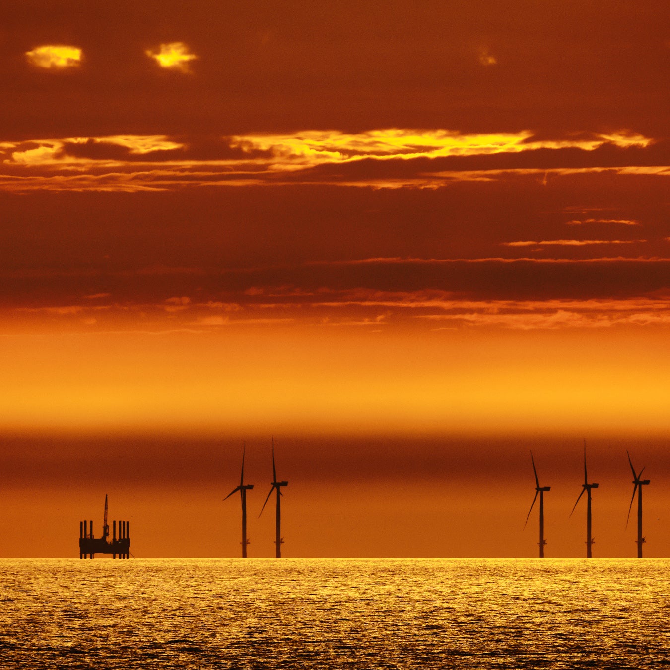 Offshore windmills alongside an oil rig