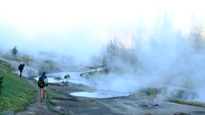 Monica and Aiden in Yellowstone National Park, walking a geyser basin in the early morning