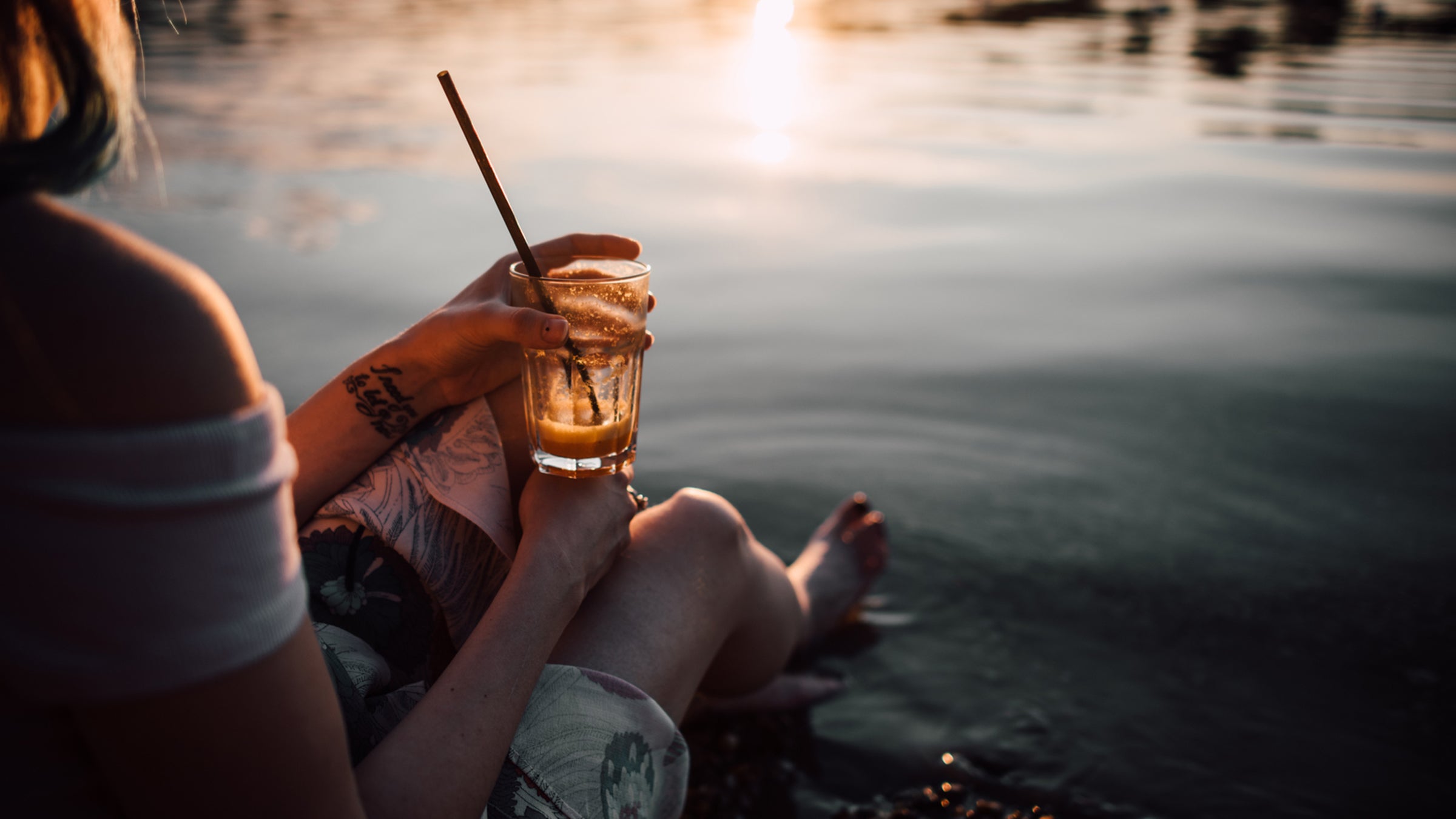 Young Woman Having A Drink And Sitting On The Beach