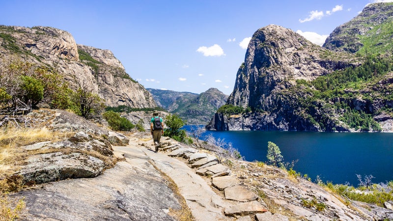 Hiking on the shoreline of Hetch Hetchy reservoir in Yosemite National Park, Sierra Nevada mountains, California; the reservoir is one of the main sources of drinking water for the San Francisco bay