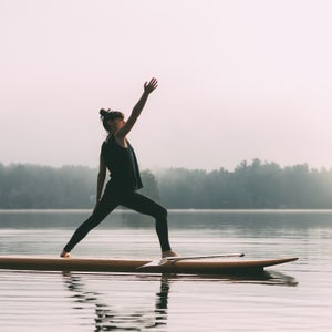 Young Woman Practicing Yoga On A Paddleboard