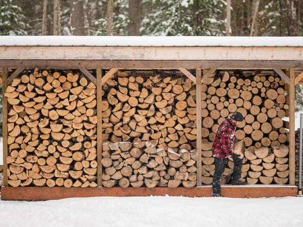 Man With Flannel Jacket Stacking Wood At Cottage Winter Wood Pile