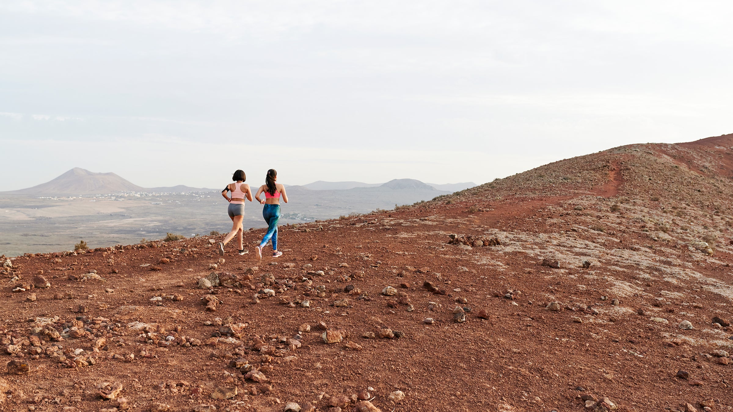 Women Running Together Along A Rugged Trail