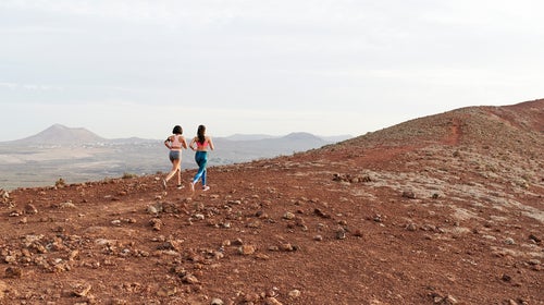 Women Running Together Along A Rugged Trail