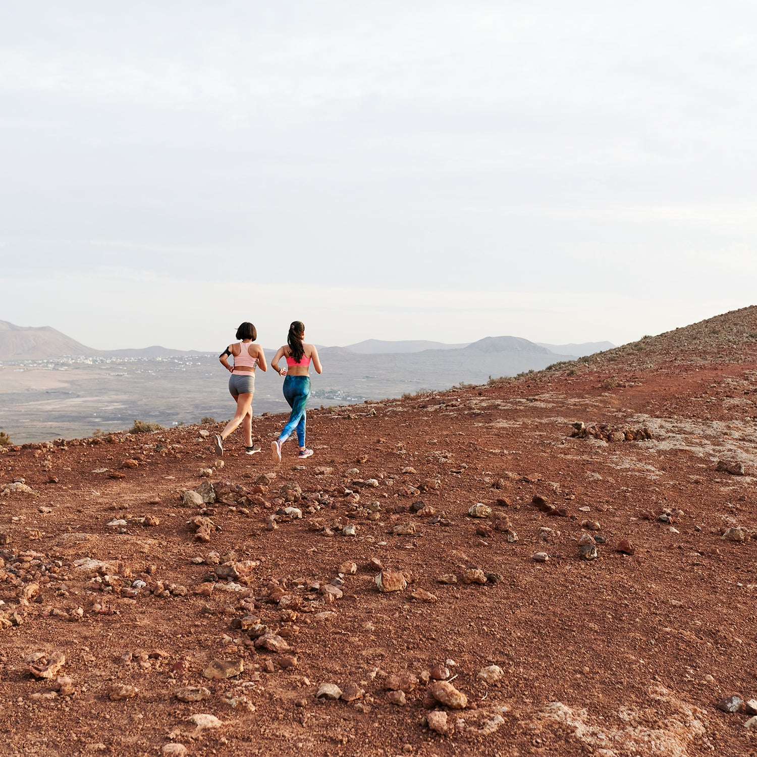 Women Running Together Along A Rugged Trail