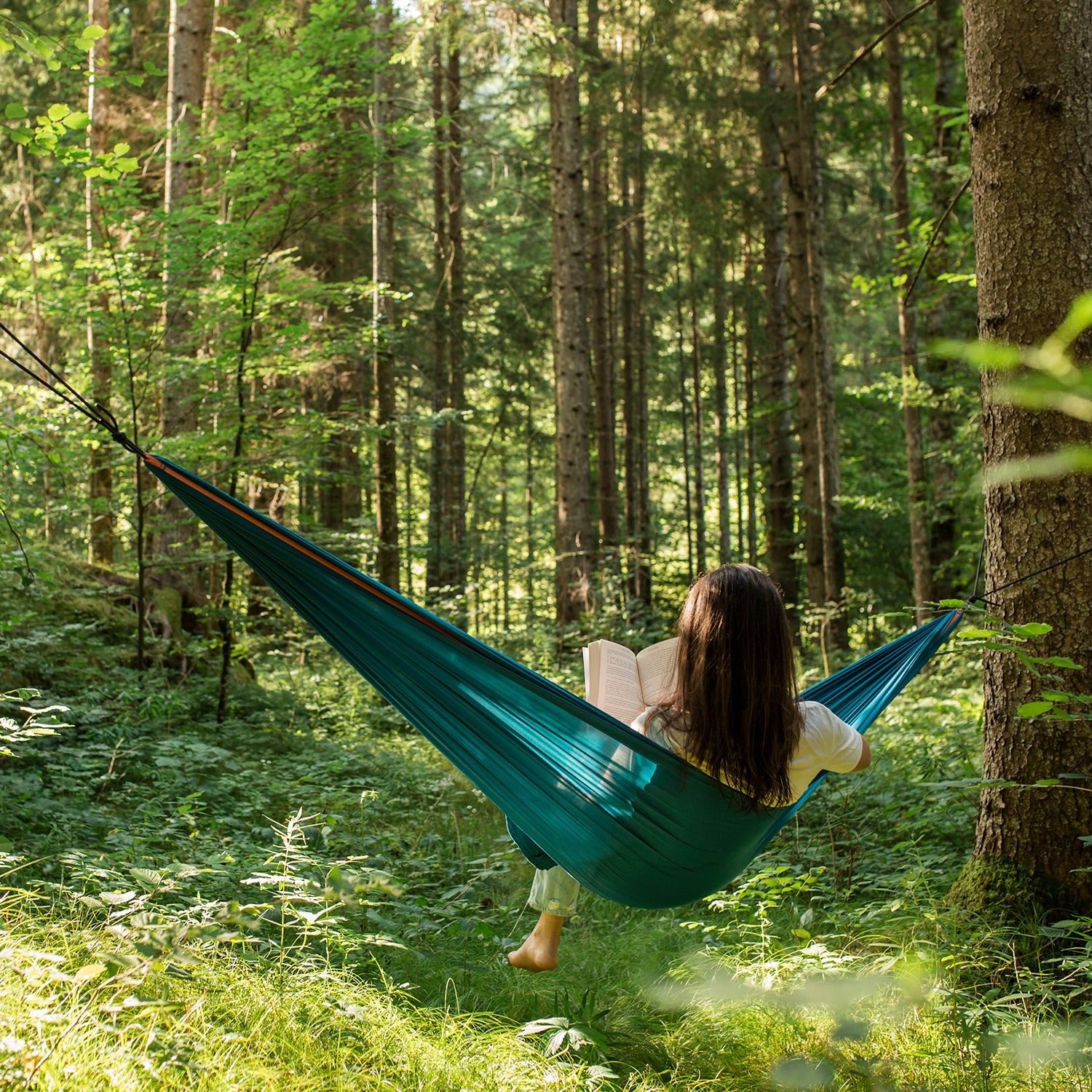 Woman Relaxing In A Hammock In A Green Forest