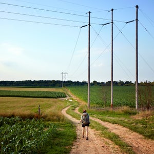 A hiker crosses on the Appalachian Trail through corn fields in pennsylvania.