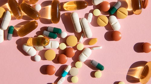 Top view of various pills and tablets on the pink background