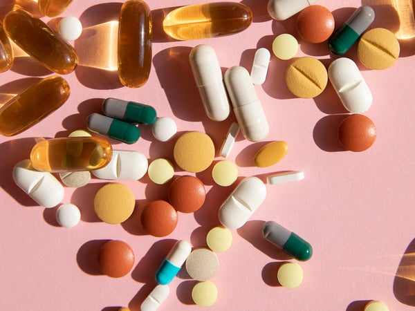 Top view of various pills and tablets on the pink background