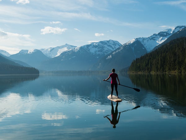 Woman stand up paddle boarding on a pristine mountain lake