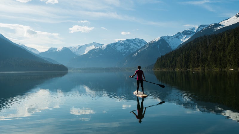 Woman stand up paddle boarding on a pristine mountain lake