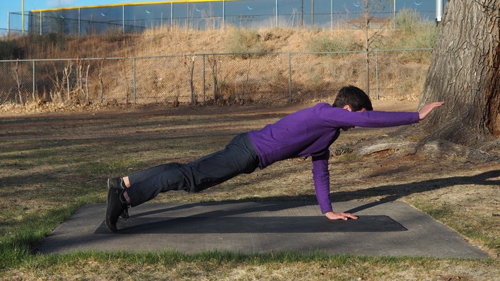 man in high plank with right arm extended forward