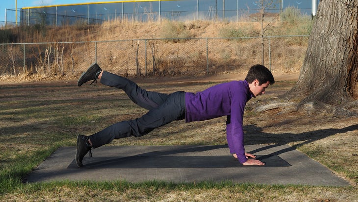 man in high plank with left leg raised backward