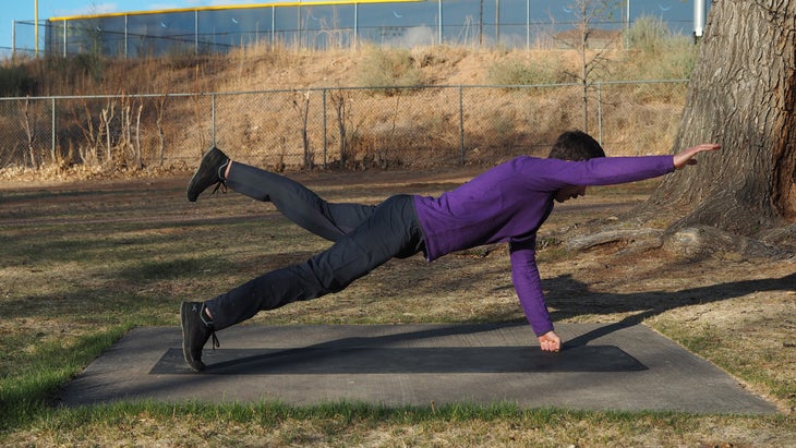 man in purple in high fist plank with right arm extended forward and right leg raised to just above hip level