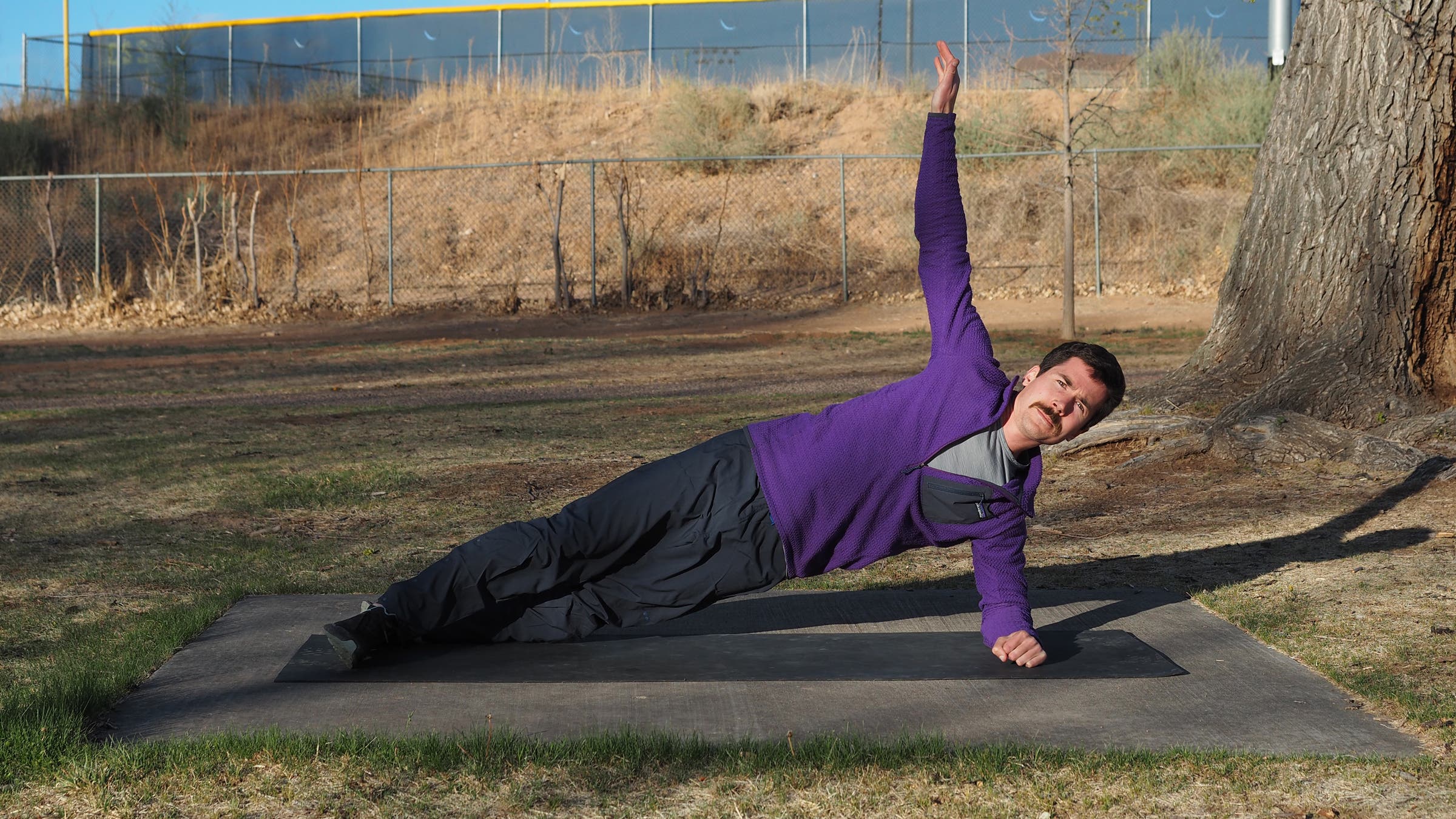 man on one elbow in a side plank with his opposite arm in the air
