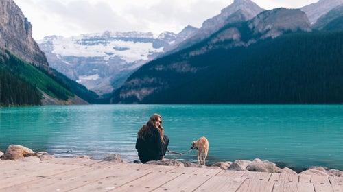 A Girl And Her Dog On A Blue Lake