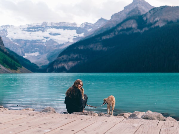 A Girl And Her Dog On A Blue Lake