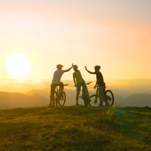 SUN FLARE: Mountain biking friends high five after reaching summit at sunrise