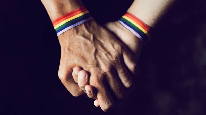men holding hands with rainbow-patterned wristband